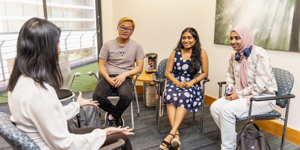 Three students listening to a counsellor provide advice during a workshop