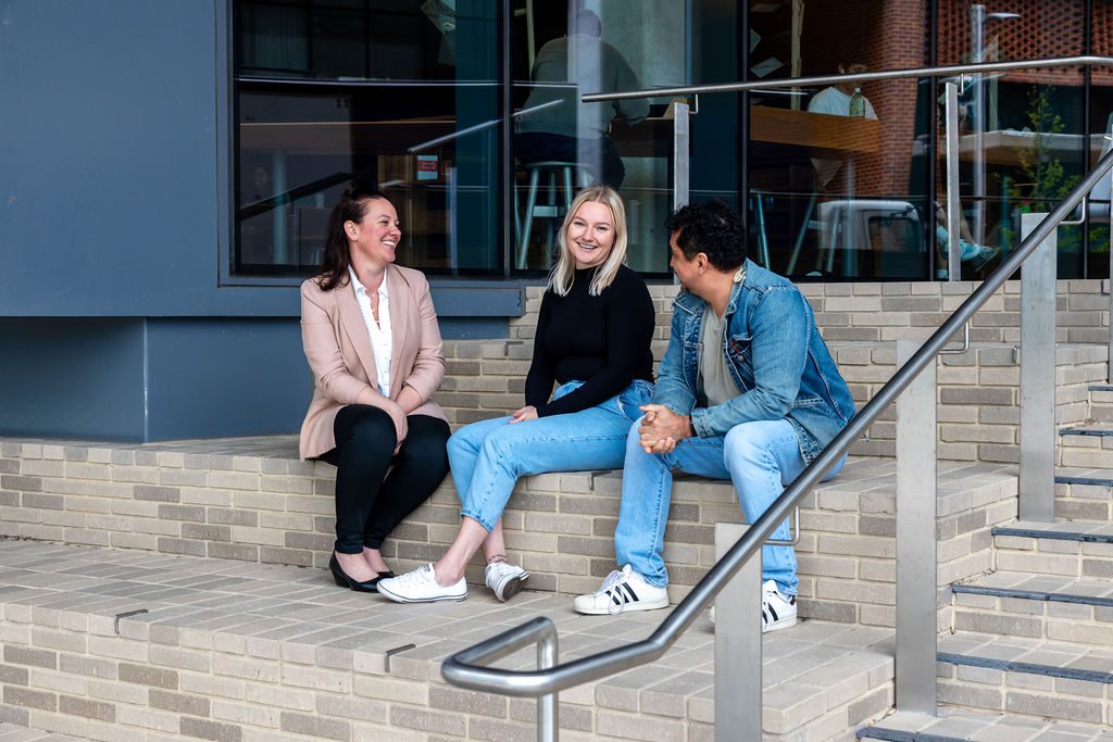 A group of people sitting on the steps of the design building