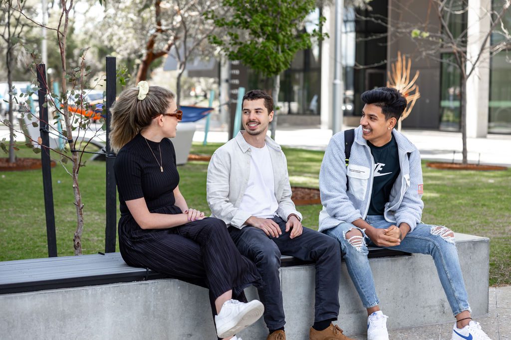 Three Curtin students sitting outside on campus