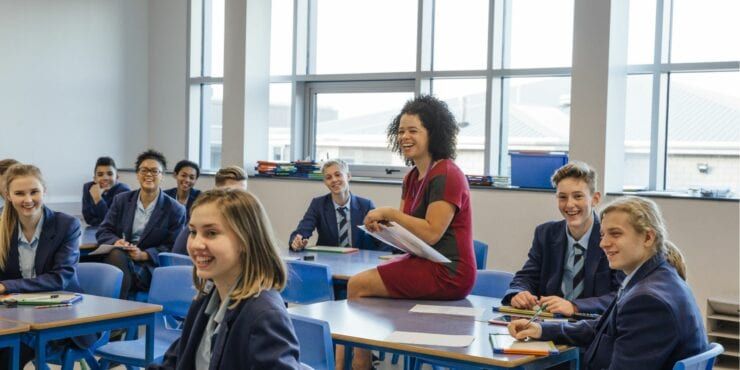 Students-in uniform and teacher smiling in the classrroom