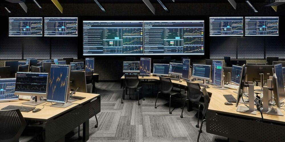 Clusters of desks facing towards large central screens inside the trading room