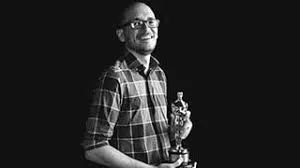 Curtin digital design graduate Andrew Joseph holding an award in front of a dark backdrop.