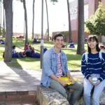 Two students sit in front of the Curtin pines