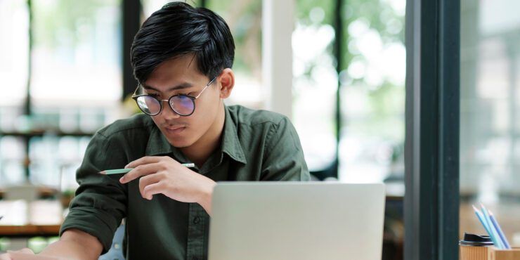 Young male student wearing glasses in front of a laptop