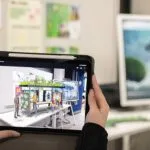 A female teacher, holding a tablet up to show a male teacher