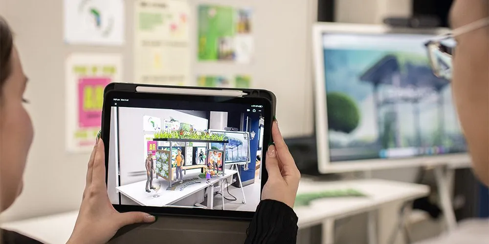 A female teacher, holding a tablet up to show a male teacher