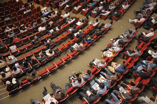 View of people sitting in auditorium seating from above.