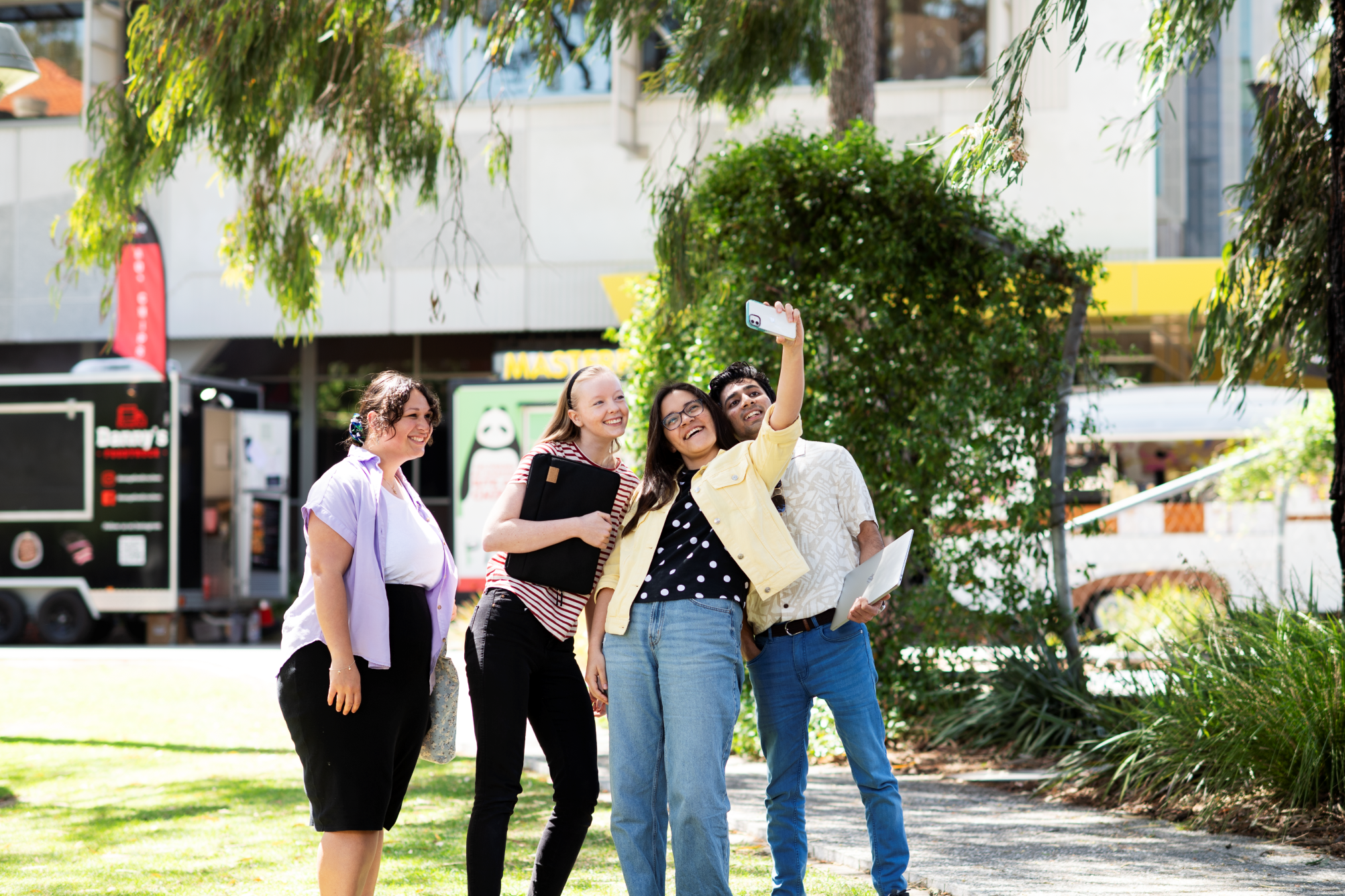 Four students are gathered around taking a selfie.