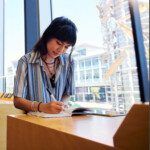 Postgraduate student sitting at a desk and taking notes