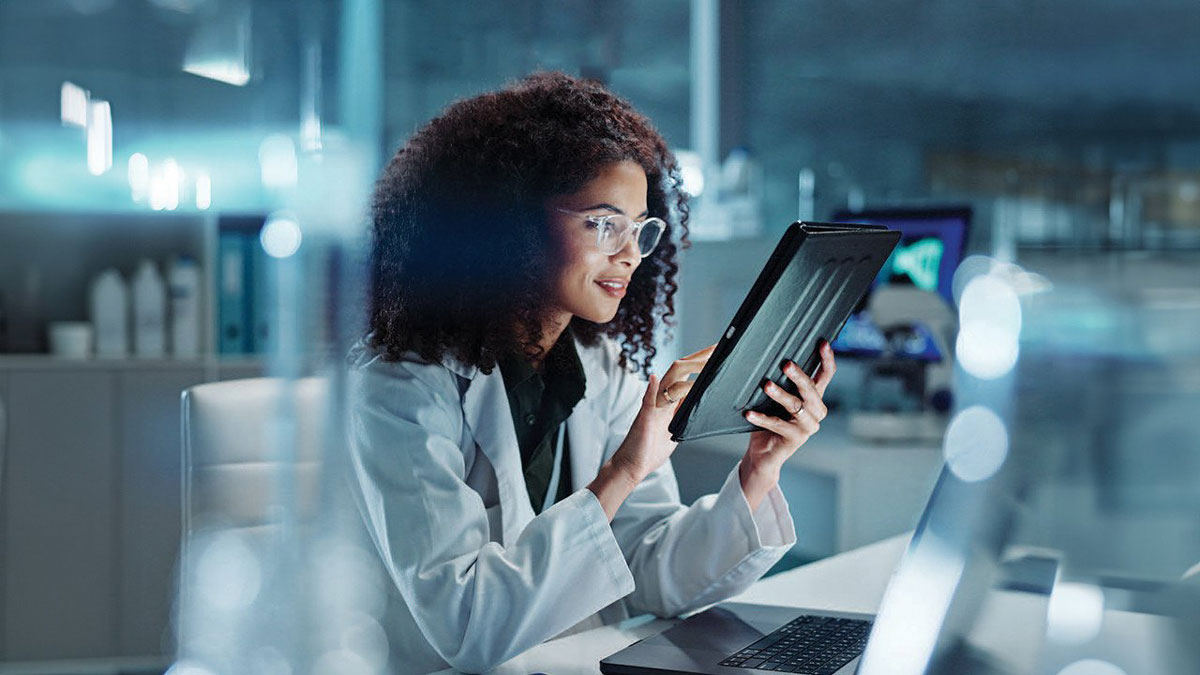 Person in lab coat working on a tablet.