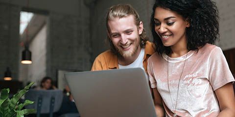 Portrait of young man and girl sitting in restaurant and working on laptop.