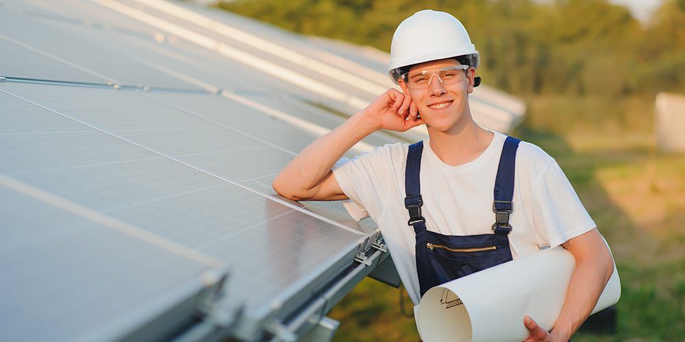 high school student standing next to a solar panel