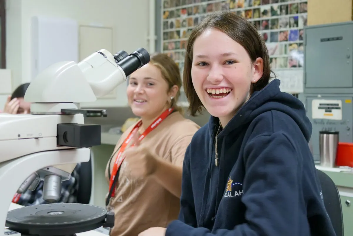 Girl at a microscope smiling