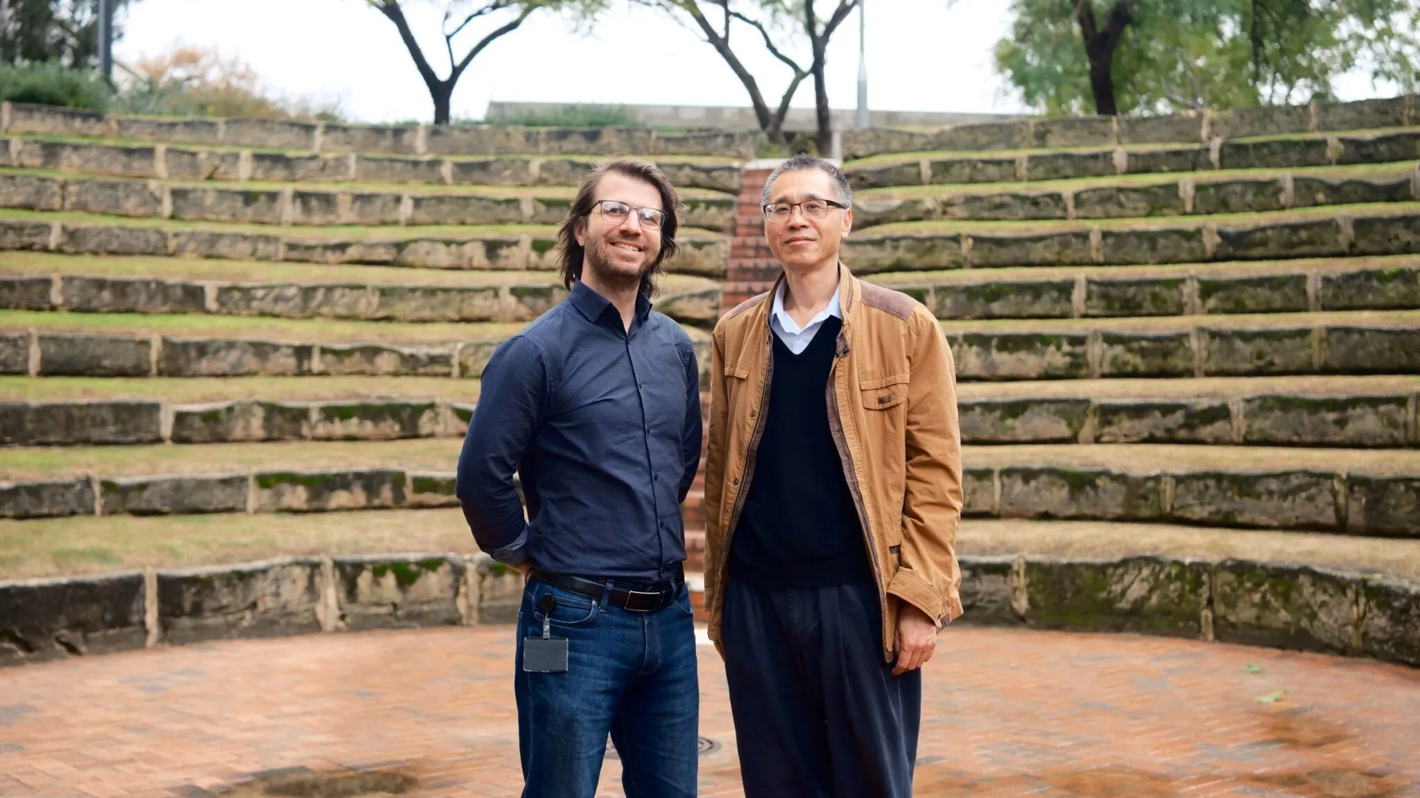 Two Minerva project team members standing outdoors in front of stone steps, dressed in casual and business-casual attire.