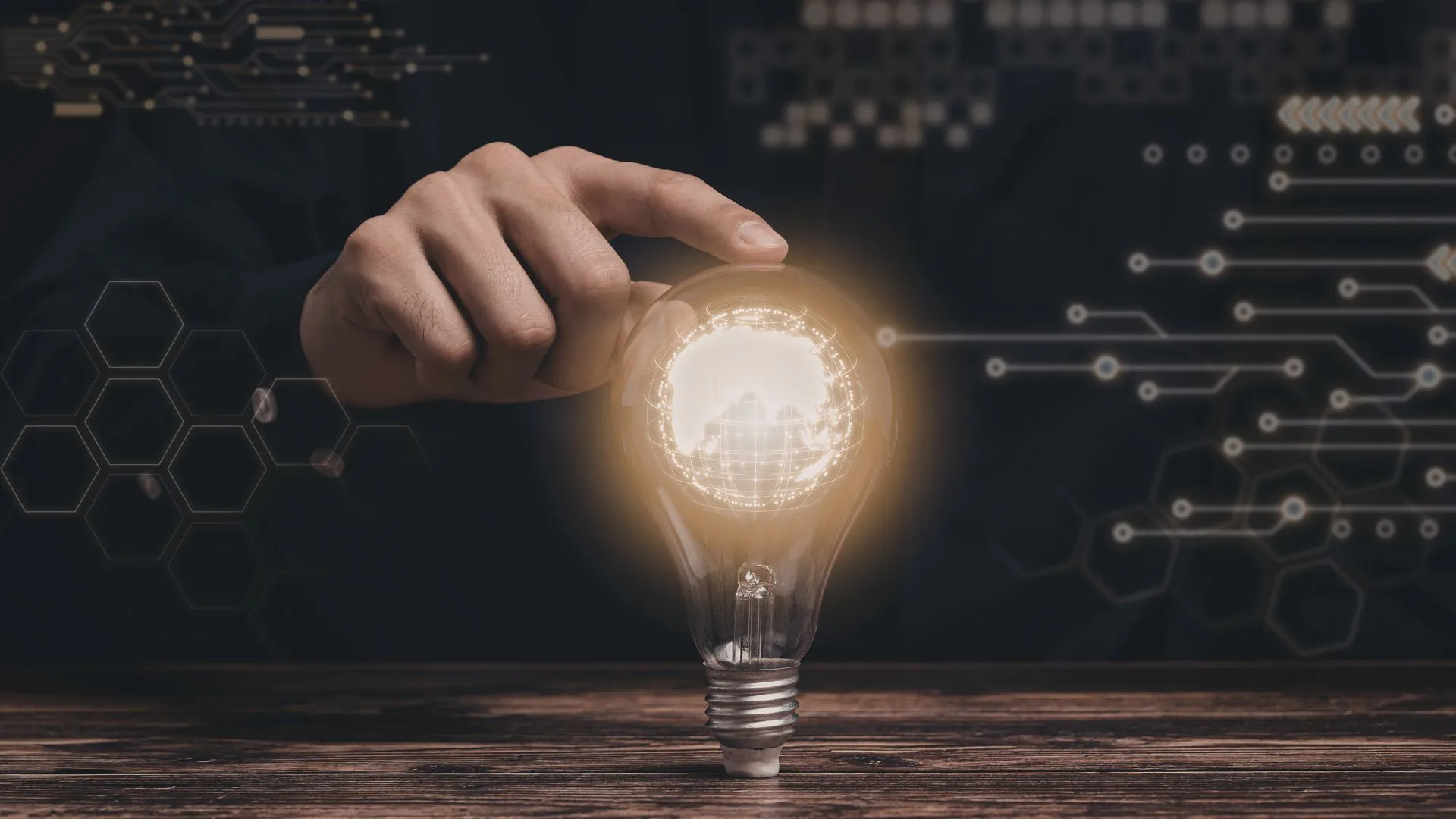 A hand reaching toward a glowing lightbulb, symbolising innovation, ideas, and creativity.