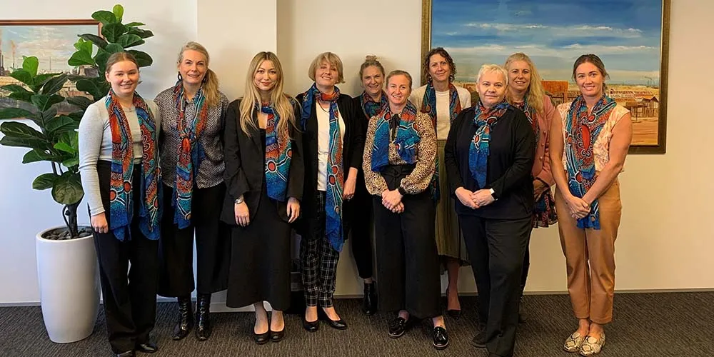 Ten woman standing and smiling wearing the Moorditj Yorga scarves
