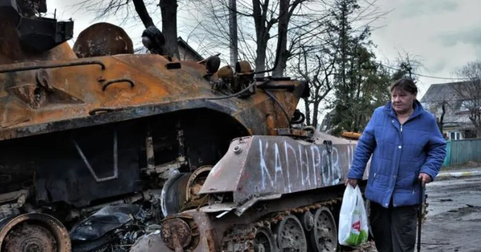 Woman walks past blown up Russian tank