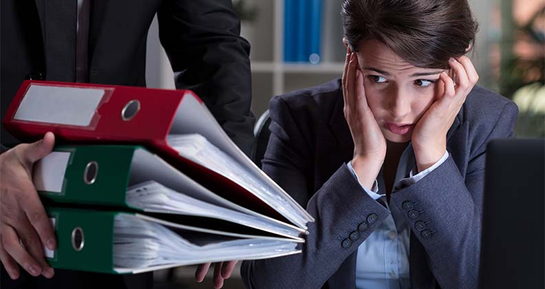 Girl looking overwhelmed siting at desk with lots of files.