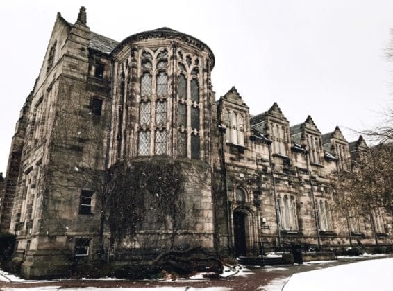 Old stone historic building, New King's, with wintered vines stands against a grey crisp sky.