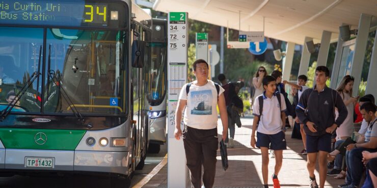 Students walking through a bus stop after getting off the bus