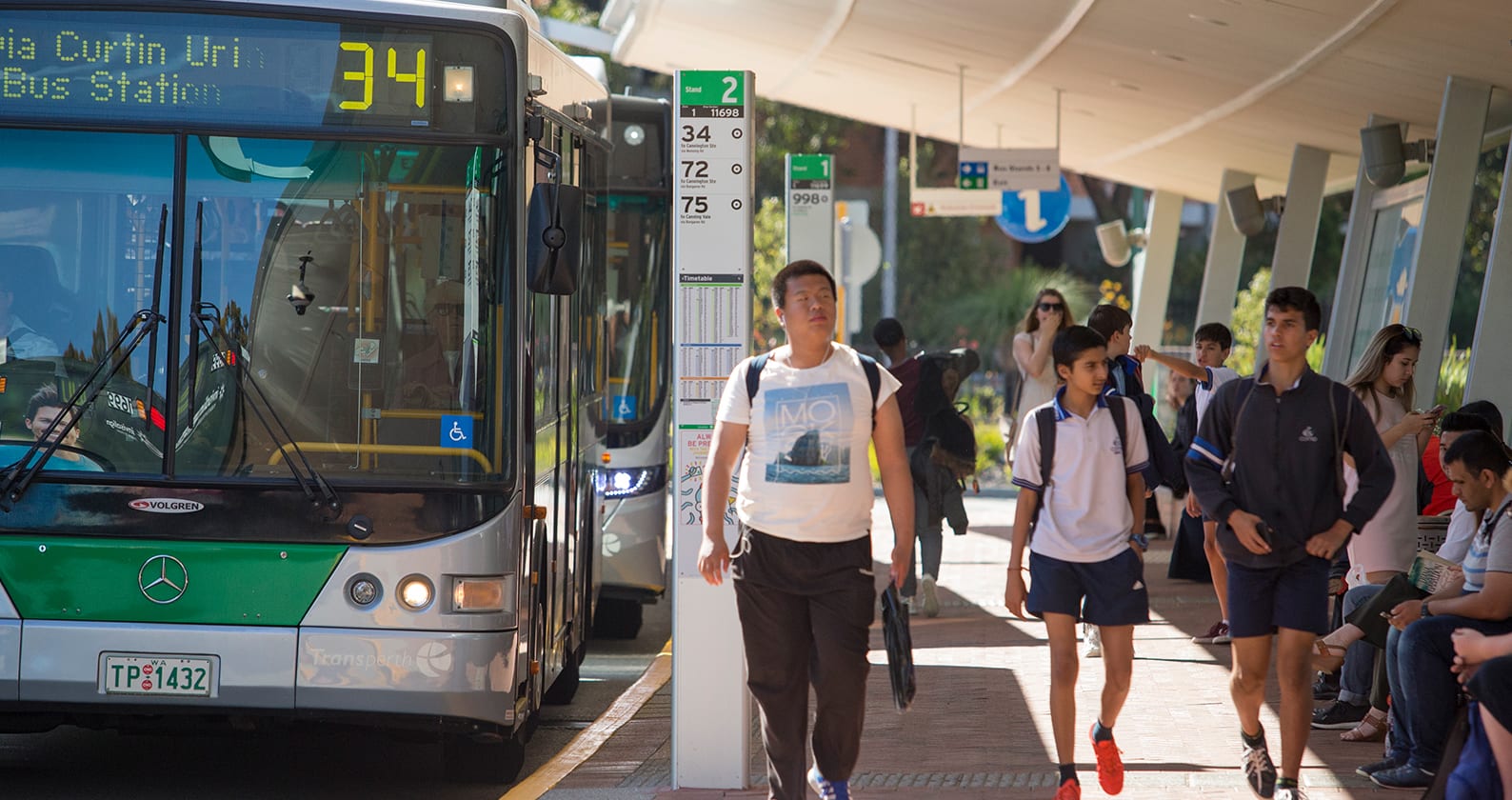 Students walking through a bus stop after getting off the bus