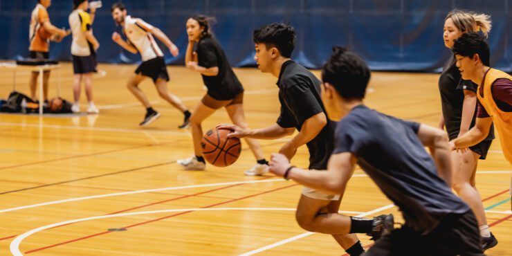 Group of students playing basketball indoors.