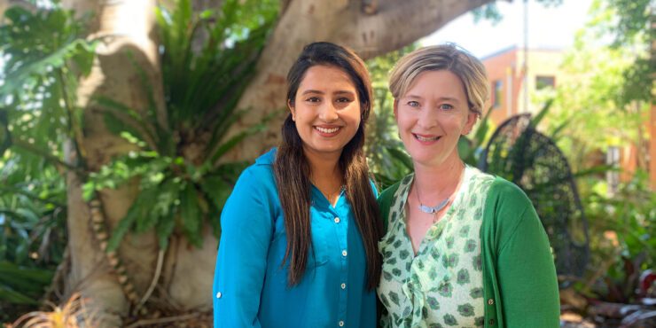 Anjali and Nina stand together and smile at the camera.