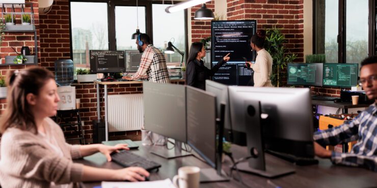 Team of programmers analyzing machine learning app code on programming big screen, standing in it company office. Software developers working on database system with html script