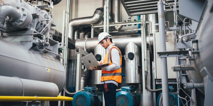 Professional worker in modern factory using laptop.