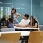 A group of students in conversation around a library desk.