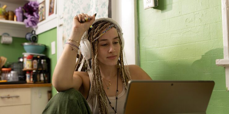 A student with headphones observing something on her laptop.