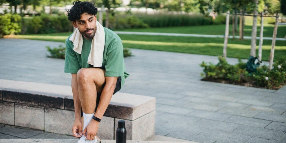 A student tying their shoelaces on a morning workout outdoors.