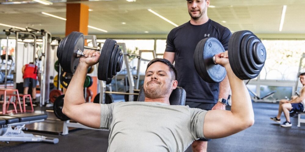 Gym member holding two dumbbells. 