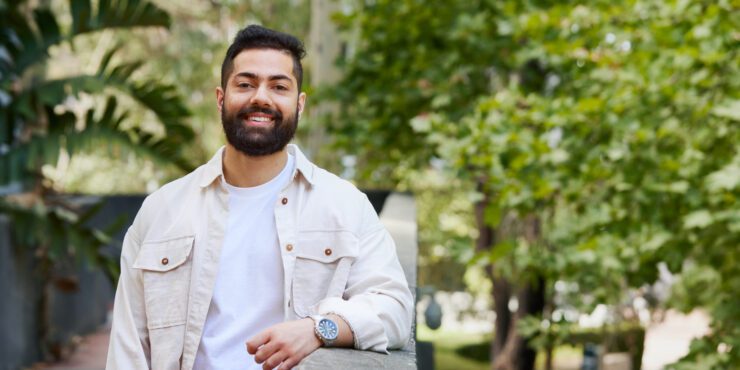 Student wearing a white button up shirt, leaning on a wall