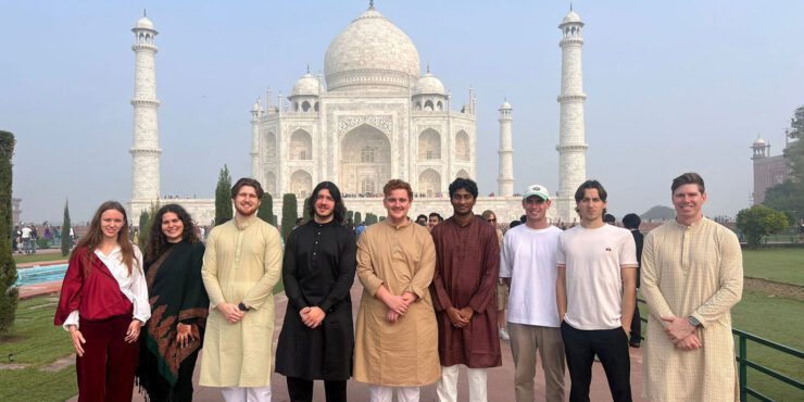 A group of business and law students standing in front of the Taj Mahal in India.