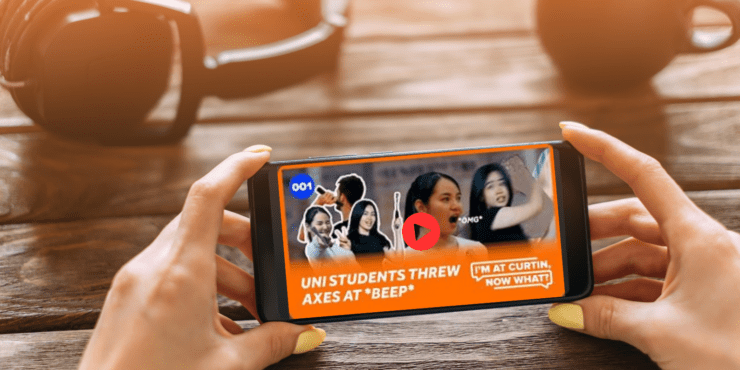 Someone holding an iPhone with the latest I'm At Curtin Now What video playing.