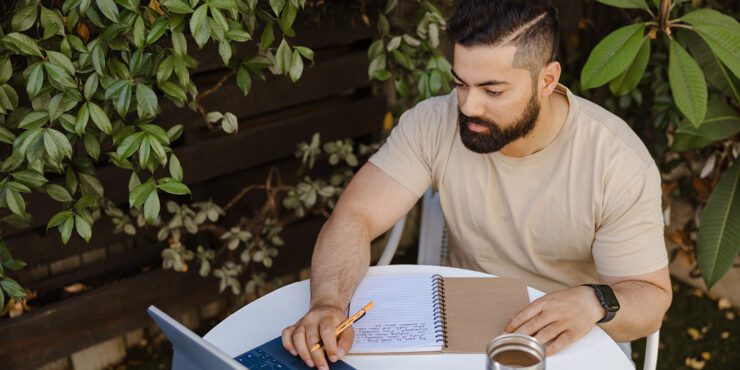 Student works at their device whilst sitting outside.