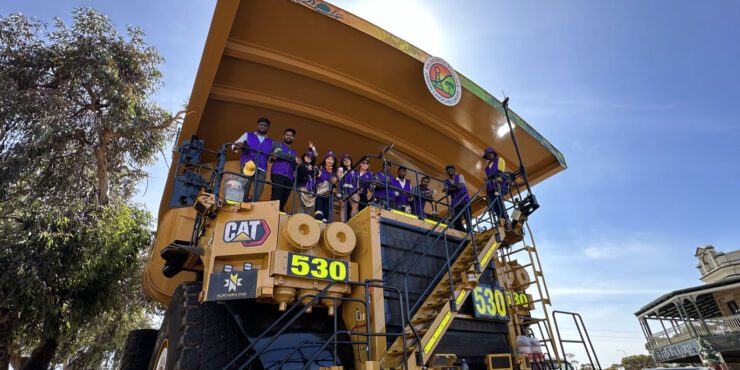 A large mining truck with students posing for a photo at its helm.