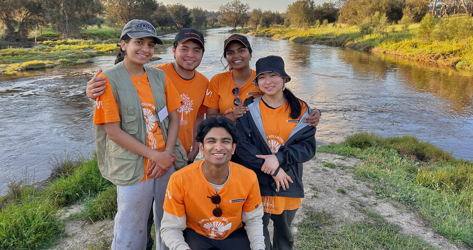A group of Curtin Volunteers in front of a lake.