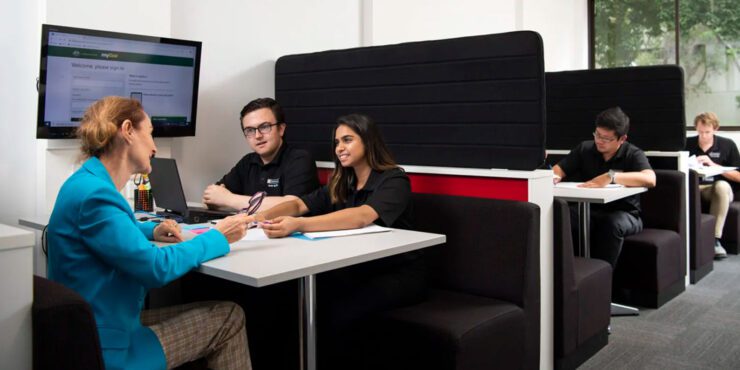 A group of booths with students and staff sitting in each one.