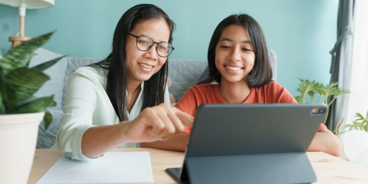 A mum and daughter look at a tablet together.