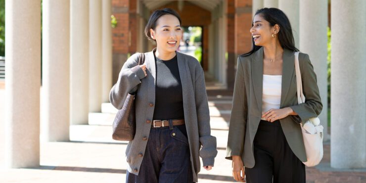 Two women in suits laughing.