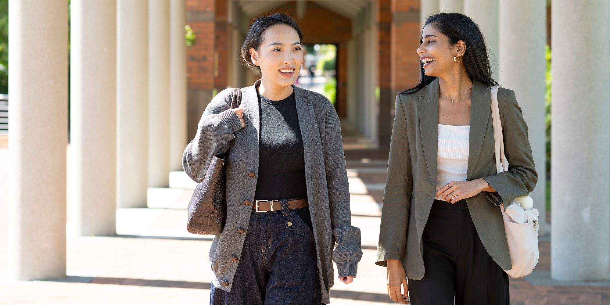 Two women in suits laughing.