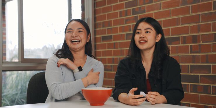 Celena and Devna sit at a table selecting questions out of a bowl.