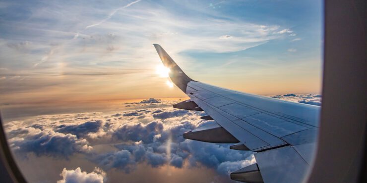 A view from inside a plane out a window looking at the sky and a plane wing.