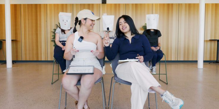 Devna and Celena sitting in front of masked students.