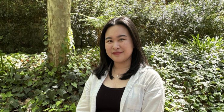 Darcey a final-year Master of Commerce student smiles at the camera wearing a black singlet and white shirt open over the top.
