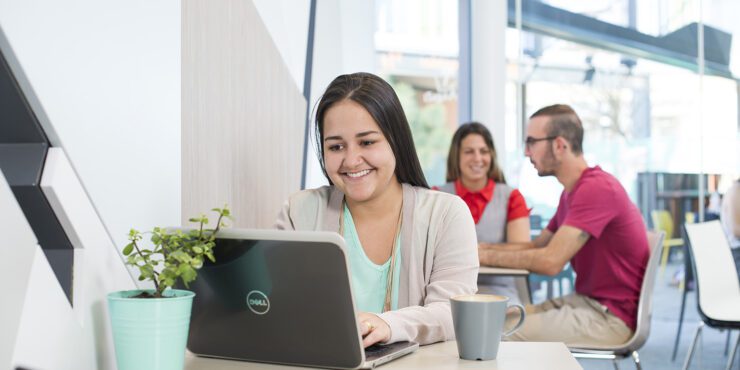 Woman with a laptop open in front of her, sitting in a cafe