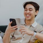 A male student smiling while looking at his phone