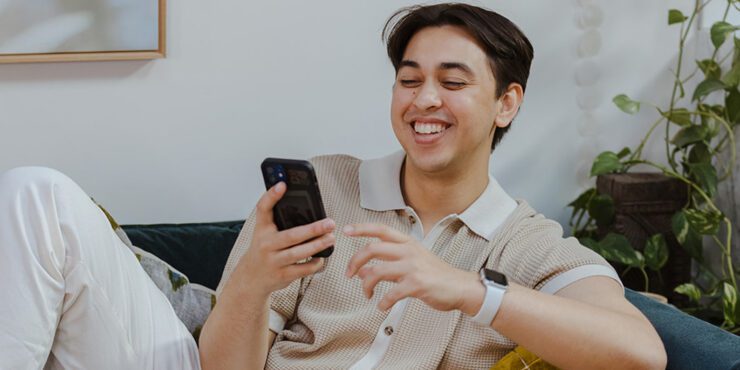 A male student smiling while looking at his phone